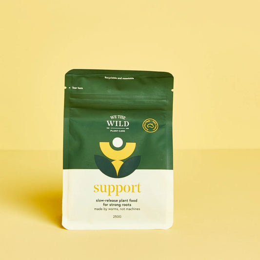 Green and white package of 'We The Wild' Support Organic Slow Release Plant Food plant food 250g resealable bag on a yellow background