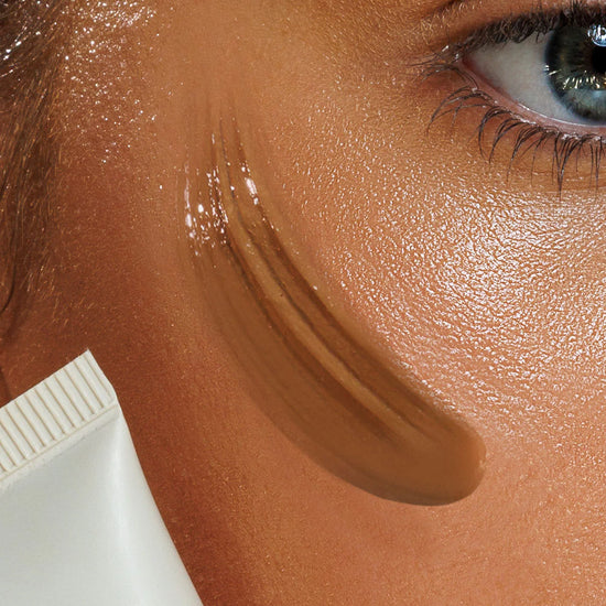 Close-up of a person applied brown makeup to their face with a small tube.