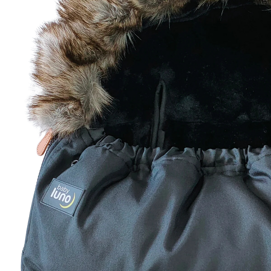 Close-up of a black baby footmuff pram liner with fur hood and 'baby luno' label 
