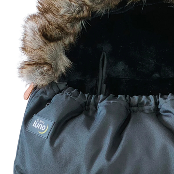 Close-up of a black baby footmuff pram liner with fur hood and 'baby luno' label 