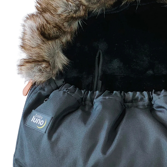 Close-up of a black baby footmuff pram liner with fur hood and 'baby luno' label 