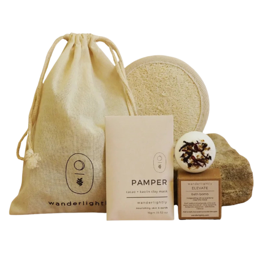 Collection of natural skincare products including a drawstring bag, soap, and bath bombs on a white background. Mini spa hamper 