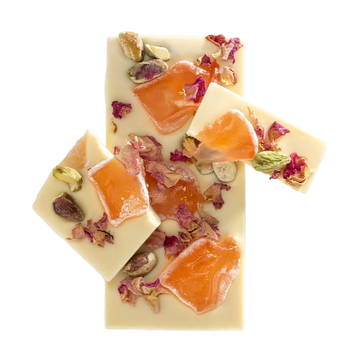 Three pieces of white chocolate with orange slices, dried fruits, and flowers on a white background