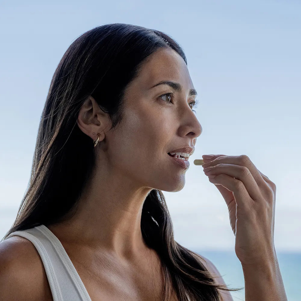 Woman taking vitamin outdoors with a clear sky background