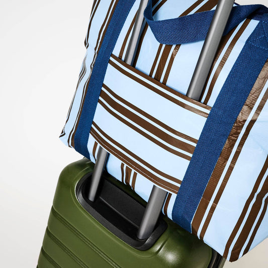 Green suitcase with a Zip Medium Tote  Oxford Stripe on top against a light background