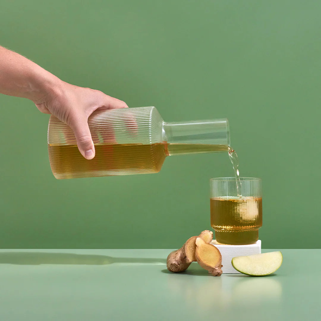 apple & ginger hydramama being poured into glass with apple and ginger sitting