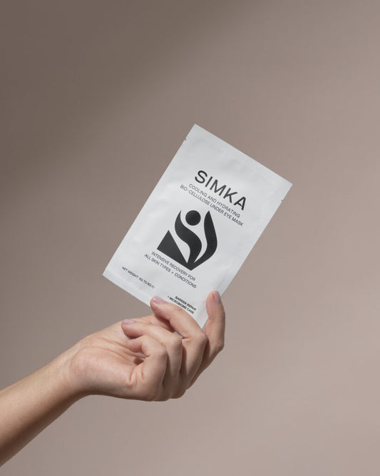 Hand holding a SIMKA product package against a beige background