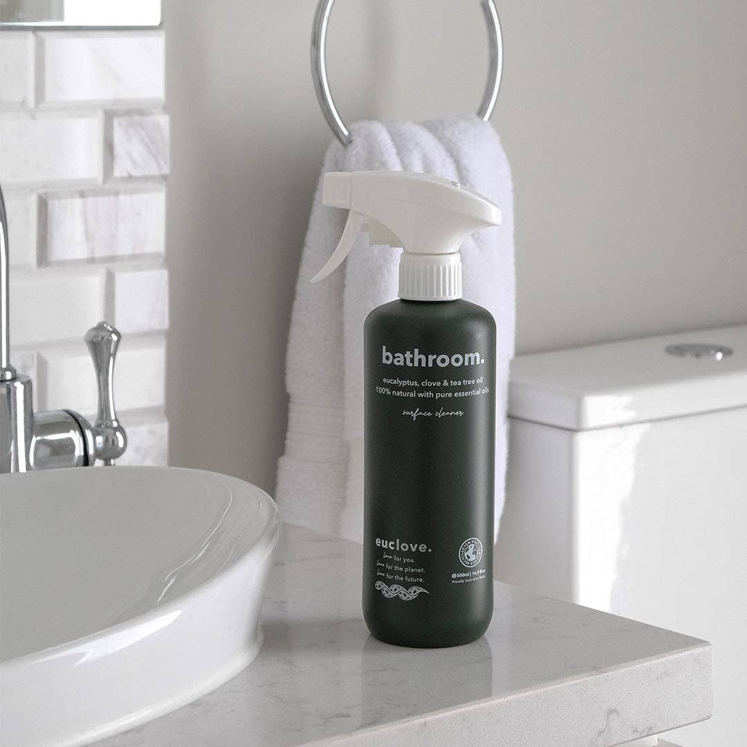 Bottle of euclove bathroom cleaner on a bathroom counter with a white towel and sink in the background.