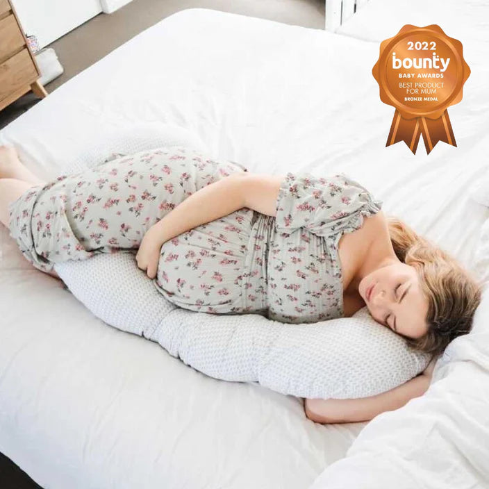 Woman lying on a bed with a pregnancy pillow, 2022 Bounty Baby Award badge visible.