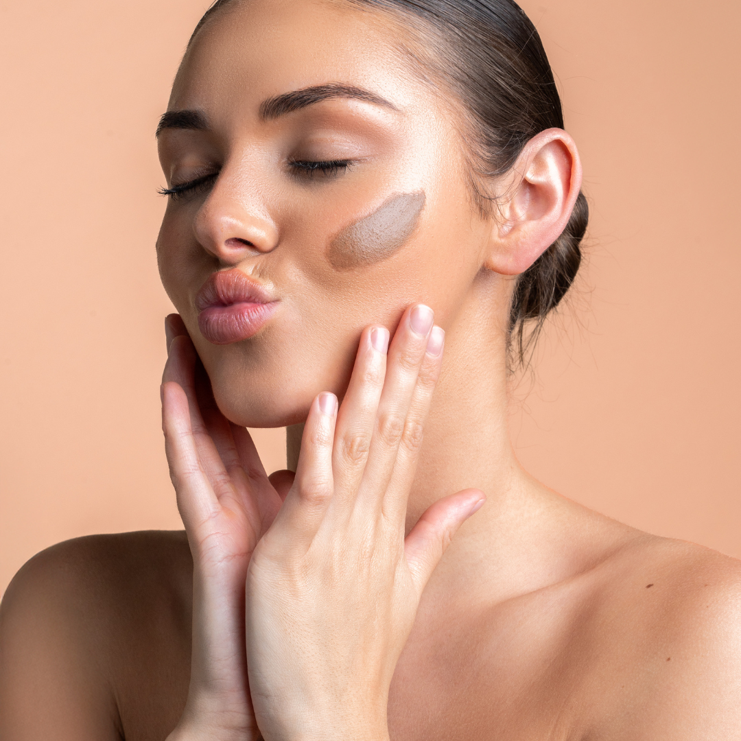 Woman applying bronzer with a neutral background