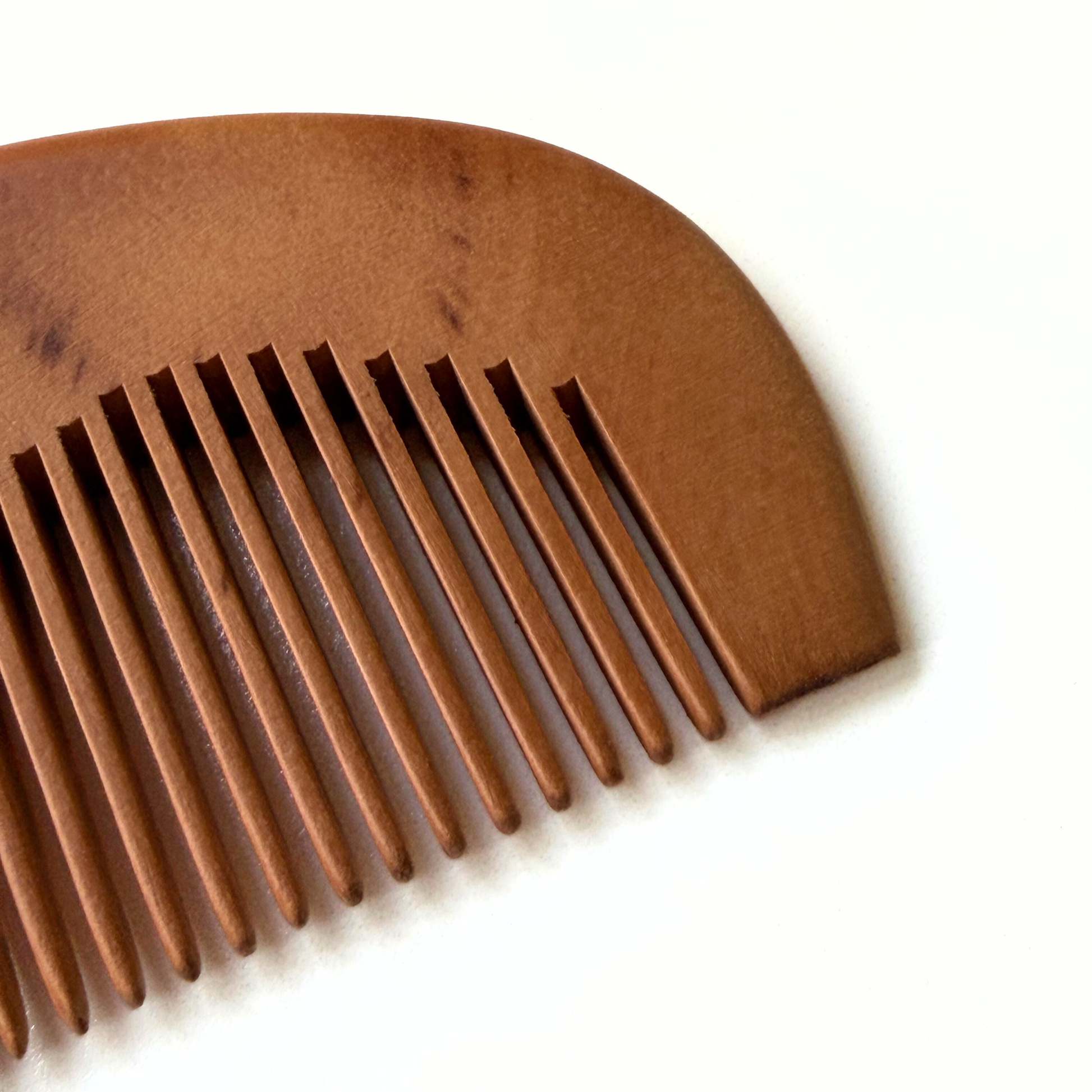 Brown baby wooden comb close up of bristle on a white background