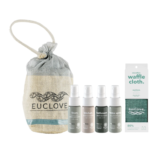 A home fragrance gift set from Euclove including a beige burlap drawstring pouch, four small spray bottles in linen, kitchen, bathroom, and home spray scents, and a white waffle cloth.