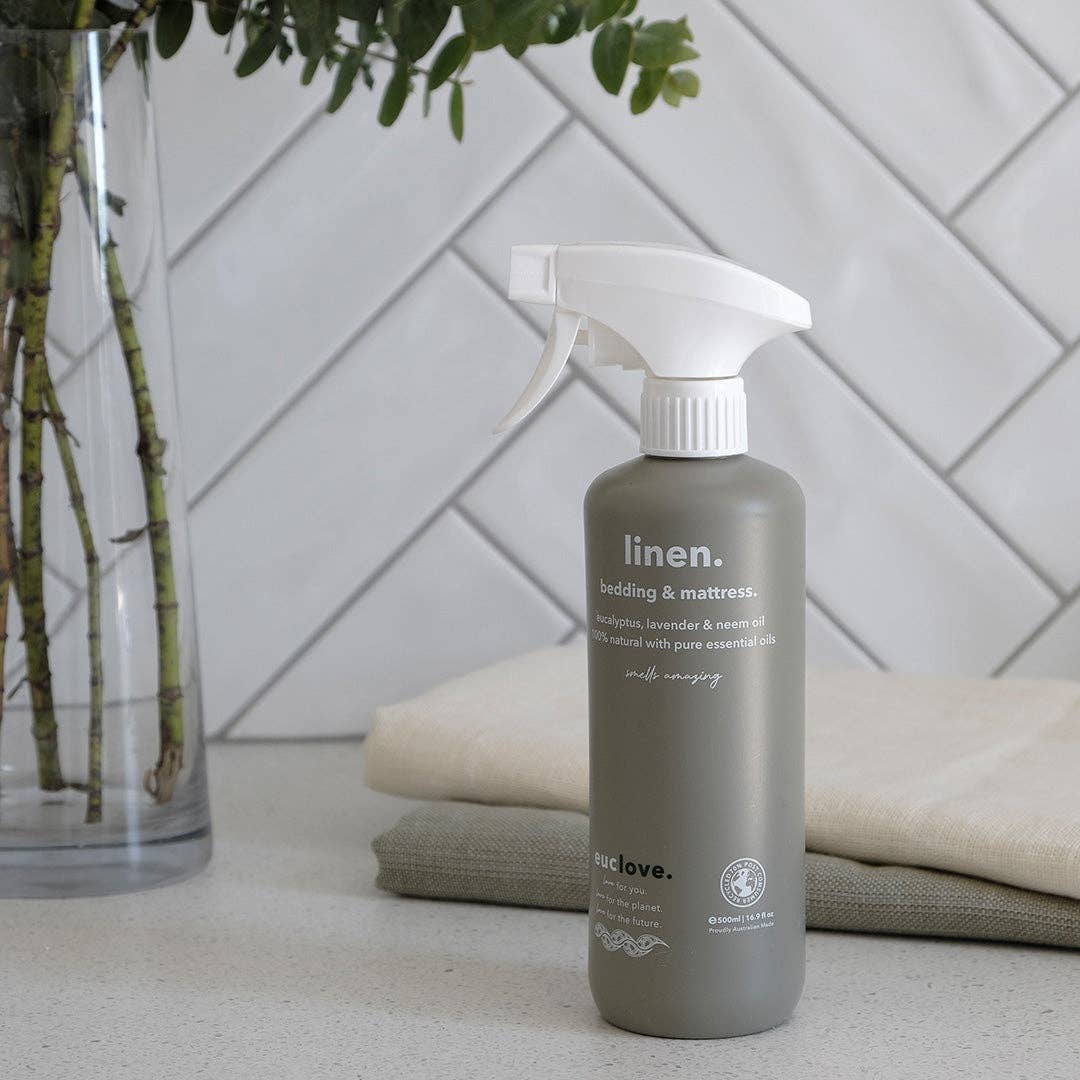 Linen spray bottle on a surface with a geometric wall pattern in the background