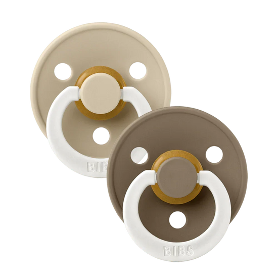 Two baby pacifiers in beige and brown with white rings