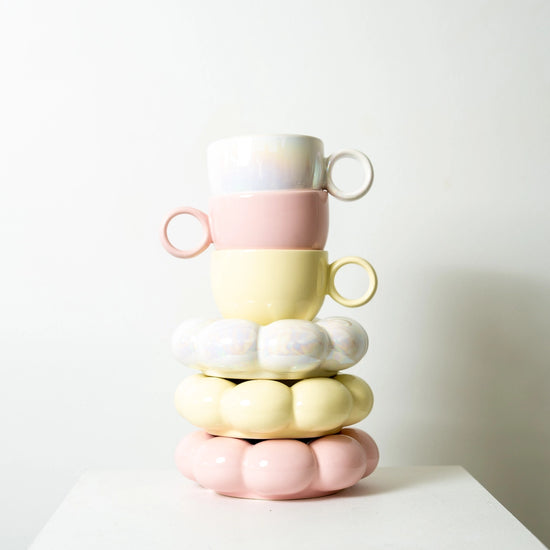 Stack of pastel-colored ceramic cups on a white surface with a light gray background