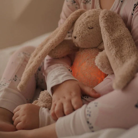 Child holding a glowing plush bunny toy in a soft, warm setting