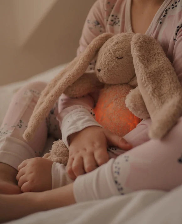 Child holding a glowing plush bunny toy in a soft, warm setting