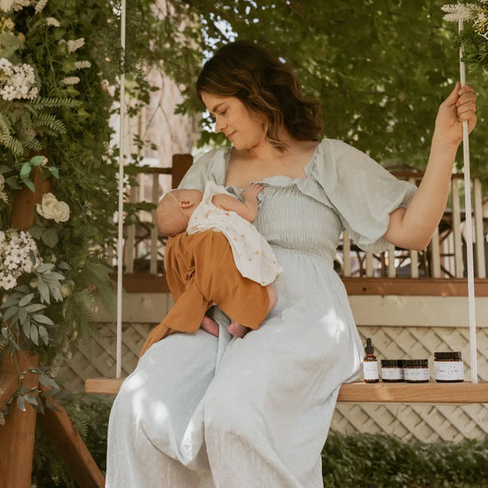Woman breastfeeding a baby on a swing with a natural setting