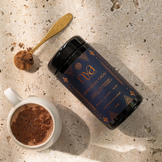 Nya cacao powder container with a cup of cacao and a spoonful of cacao on a textured surface