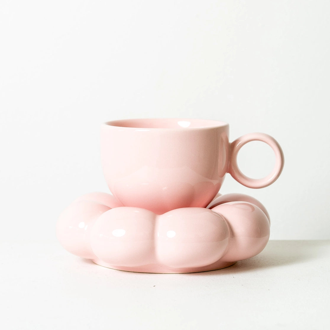 Pink ceramic cup and saucer on a white background