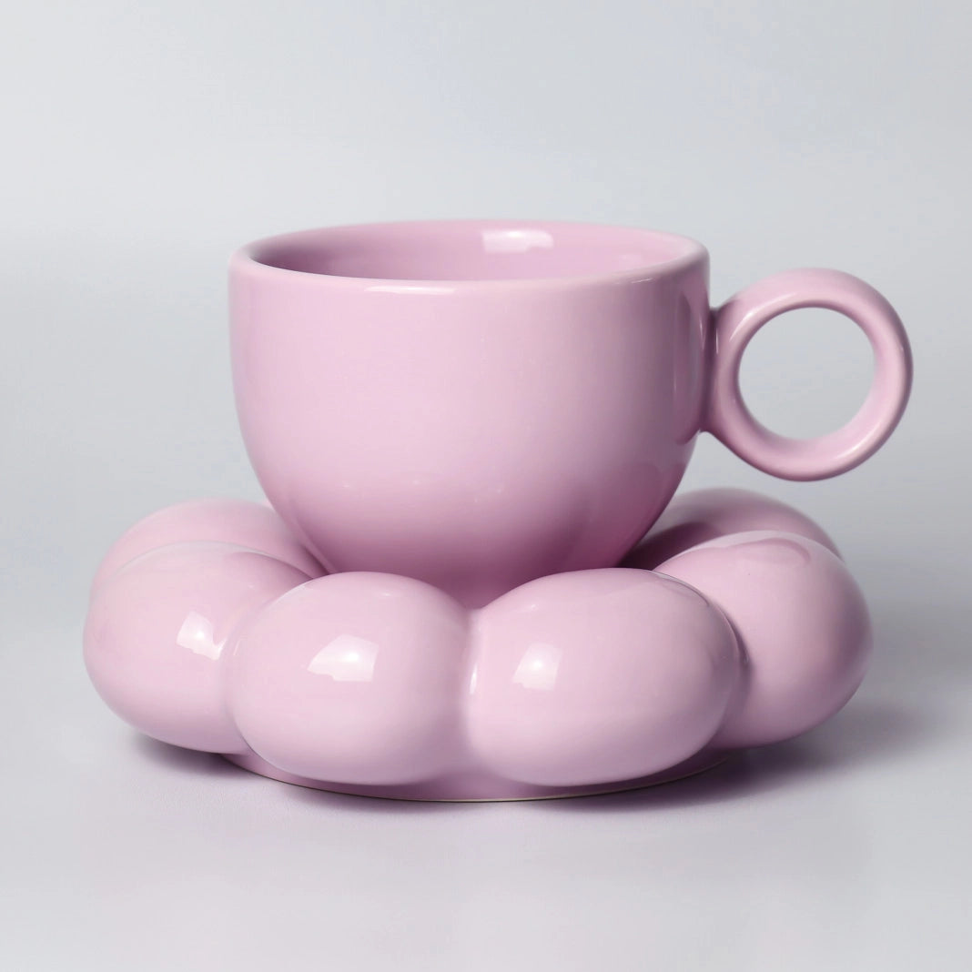 Pastel purple ceramic cup with a matching pink saucer on a light gray background