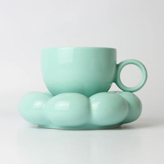 Teal ceramic cup and saucer on a light gray background