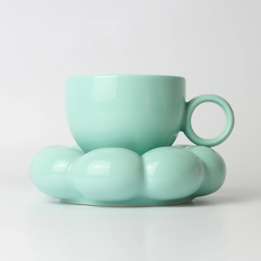 Teal ceramic cup and saucer on a light gray background