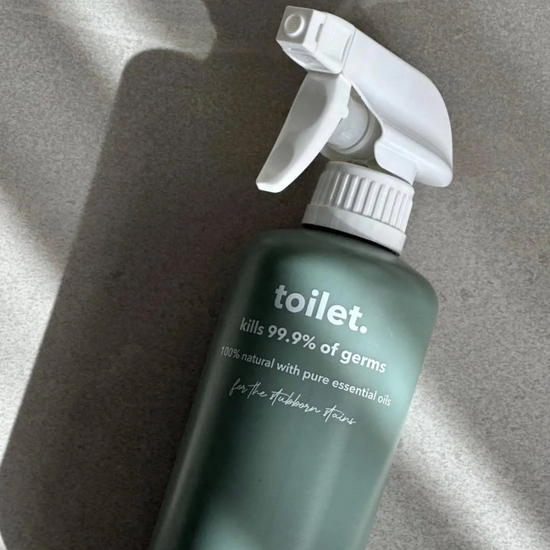 Green spray bottle labeled 'toilet' on a gray marble background