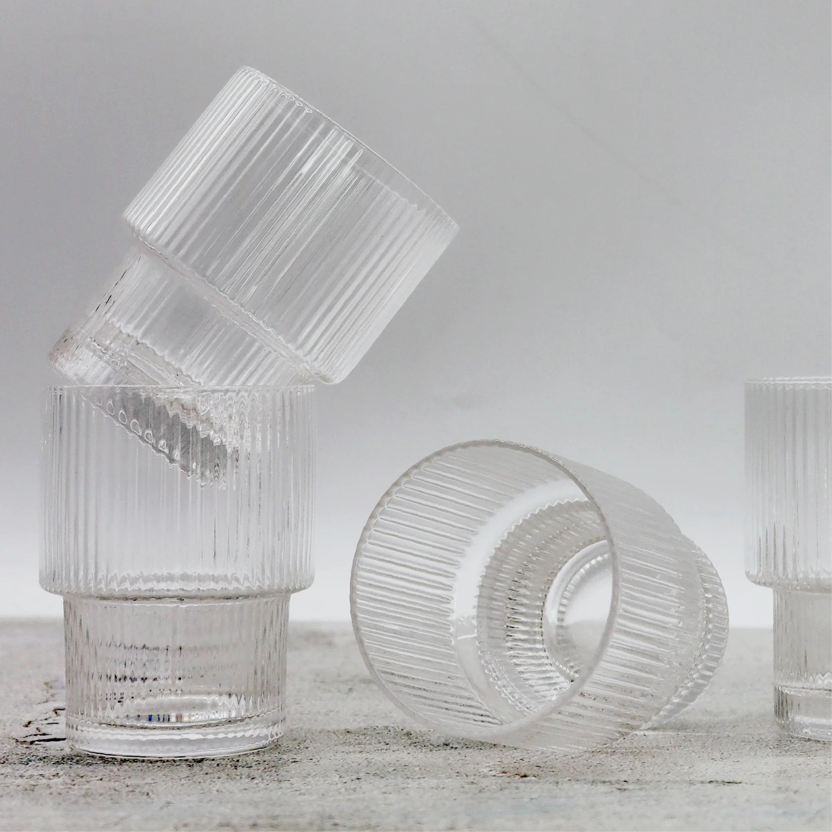 Stack of clear glass tumblers on a light gray background
